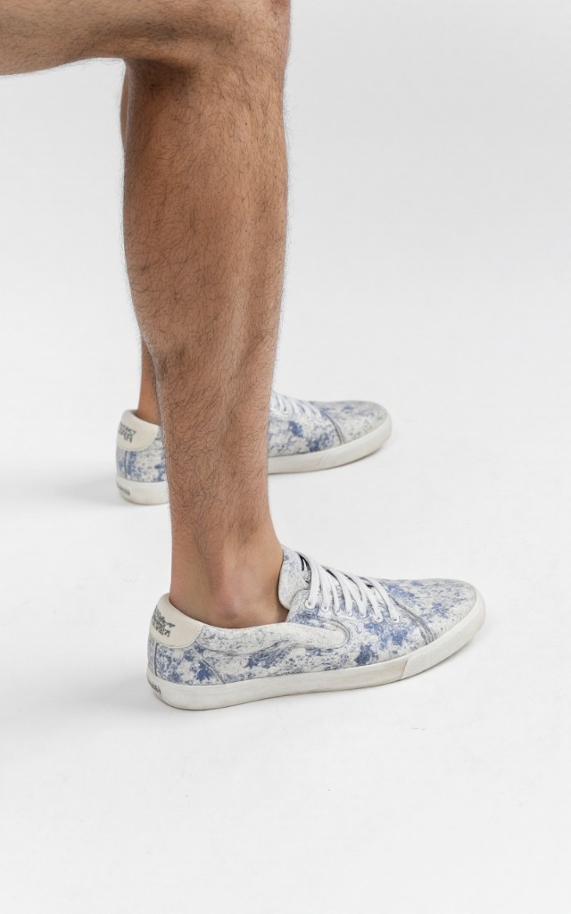 A male model wearing Sneakers, against a white background, with a close   up of the feet